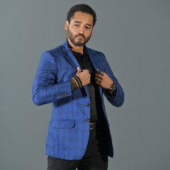 Modelo luciendo un blazer premium de cuadros en tonos azules, con una camisa negra y accesorios modernos.