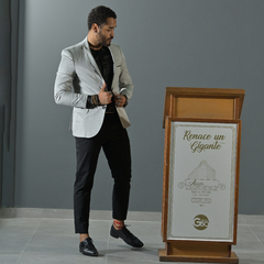 Hombre vistiendo un blazer premium slim fit gris, ajustándose la chaqueta frente a un podio.