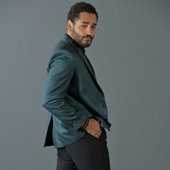 Hombre posando con un blazer slim fit de color verde inglés, mirado hacia la cámara.