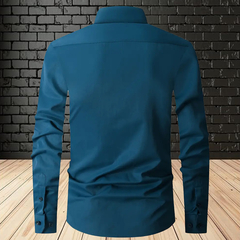 Camisa de seda slim fit en color verde jade, vista posterior, con fondo de ladrillos y piso de madera.
