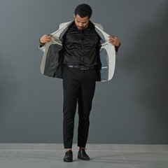 Hombre vistiendo un blazer premium slim fit de color tiza, mostrando el interior del blazer con una camisa negra y pantalones oscuros.