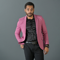 Hombre posando con un blazer premium slim fit de color rosa viejo sobre una camisa negra y pantalones oscuros.