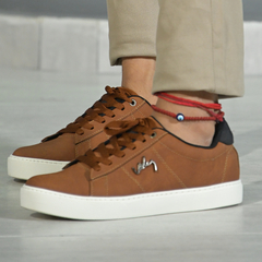 Zapato casual Siena en color marrón con detalles en negro y suela blanca, usado con pantalones claros.