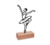 Escultura de parede em forma de bailarina, feita com contornos finos, apoiada em uma base de madeira.