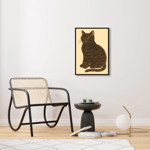 Quadro decorativo vintage de um gato preto sentado em um fundo claro, em ambiente moderno com uma cadeira e mesa ao redor.