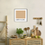Quadro decorativo com a frase "Café com Leite" em um ambiente de cozinha minimalista, com elementos naturais e utensílios.