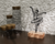 Escultura de parede em forma de bailarina, destacando uma figura elegante em pose de dança, com base de madeira.