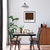 Quadro decorativo com a palavra "MACCHIATO" em fundo marrom, em uma sala de jantar minimalista com mesas e cadeiras de madeira.
