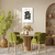 Quadro decorativo com desenho de flor preta em ambiente moderno, com mesa e cadeiras verdes.