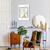 Quadro decorativo de Matisse com folhas e uma pera em um ambiente de sala de estar, ao lado de uma planta e móveis de madeira.