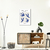 Quadro decorativo "Matisse, The Birds" com ilustrações de pássaros em azul, pendurado em uma parede clara, com móveis modernos ao redor.