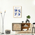 Quadro decorativo Matisse com ilustrações de pássaros em azul, em uma sala moderna com móveis de madeira e decoração minimalista.