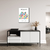 Quadro decorativo com o título "Matisse, The Garden", apresentando uma composição colorida de folhas em um fundo branco, pendurado em uma parede clara acima de um móvel moderno.