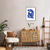 Quadro decorativo azul com a figura de uma mulher sentada, estilo moderno, em um ambiente de sala decorada.