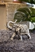 Figura decorativa de un elefante plateado con detalles ornamentales, ubicada sobre una alfombra suave.