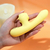 Vibrador Ponto G Baby Dragon em formato ergonômico, com textura suave e cor amarela, sendo segurado em uma mão.