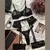Conjunto de lingerie preto com detalhes em renda, incluindo sutiã, calcinha e liga, dispostos sobre uma superfície clara ao lado de um laptop e produtos de beleza.