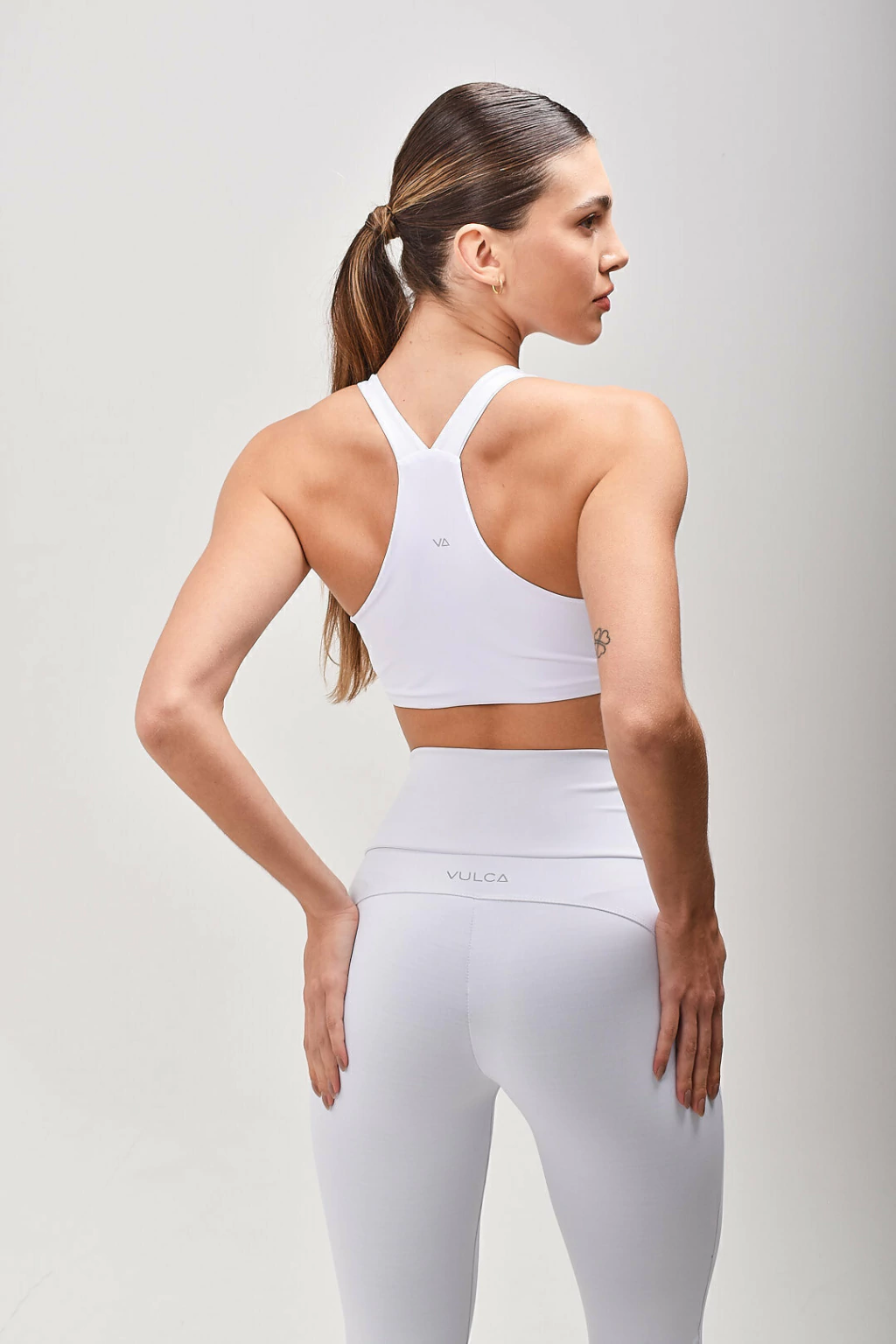 Vista traseira da Legging DuoCurve Branca Vulca, com recorte anatômico e logo Vulca no cós
