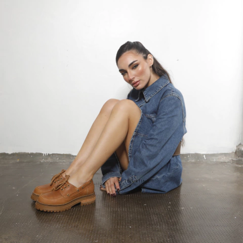 Mujer sentada en el suelo con vestido de mezclilla y mocasines color suela