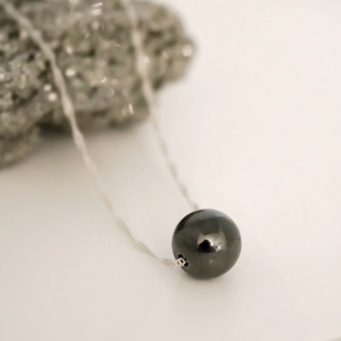 Collar minimalista con una piedra de hematita pulida en forma de esfera.
