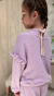 Nena con sweater Encanto de lanita lila, con volados y detalle de puntilla. Posición de espalda. 