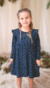 Nena con vestido de jersey estampado azul y volados. 
