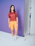 Modelo feminina vestindo a camisa Highline Territory com bretelle Moove Melado, em um fundo roxo.