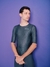 Homem usando uma camisa de manga curta cinza holográfico, com fundo roxo.