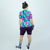Modelo feminina usando um conjunto de camisa e shorts coloridos da linha Funny Neon Euphoria, com estampas vibrantes e acessórios combinando.
