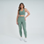 Calça legging feminina verde mescla da marca Marcio May Sports, modelo Firenze, usada com top esportivo.