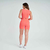 Modelo usando conjunto fitness laranja, com top e shorts, vista traseira.