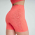 Shorts fitness laranja da linha feminina, mostrando detalhes do tecido e design na parte de trás.