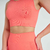 Conjunto de top e shorts fitness na cor laranja, destacando detalhes de texturização e design. Ideal para atividades físicas.