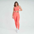Modelo vestindo conjunto de top e calça legging na cor laranja, com detalhes texturizados, em um fundo neutro.