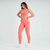 Mulher usando um conjunto laranja de top e calça legging da Marcio May Sports, posando com um sorriso.