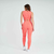 Modelo feminina usando um conjunto de top e calça legging na cor laranja, vista de costas.