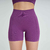 Shorts fitness femininos na cor uva, com detalhes em relevo nas laterais e cintura alta, parte de um conjunto esportivo.