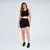 Modelo usando top feminino preto Marcio May, ideal para atividades fitness, combinado com shorts pretos.