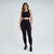 Calça legging feminina preta da marca Marcio May, modelo Romilla, com detalhe em textura e uso de top cropped.
