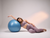 Mulher relaxando ao lado de um bola de ginástica, vestindo calça legging feminina rosa mescla da marca Marcio May Sports.