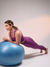 Mulher realizando exercício de plank sobre uma bola de ginástica, vestindo calça legging feminina roxa da marca Marcio May Sports.