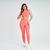 Modelo vestindo um conjunto de top e calça legging laranja da marca Marcio May Sports.