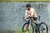 Homem sentado em uma bicicleta, usando a camisa de ciclismo Márcio May Pro Peach, com um fundo natural.