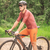 Homem usando a camisa de ciclismo Márcio May Aero Caju, montado em uma bicicleta, em um ambiente natural.