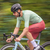 Atleta em movimento, vestindo a camisa de ciclismo Márcio May Aero Pistache, pedalando em uma bicicleta em um ambiente natural.