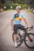 Homem em uma bicicleta, usando um kit de ciclismo azul com detalhes em vermelho, amarelo e preto, representando a Bélgica.