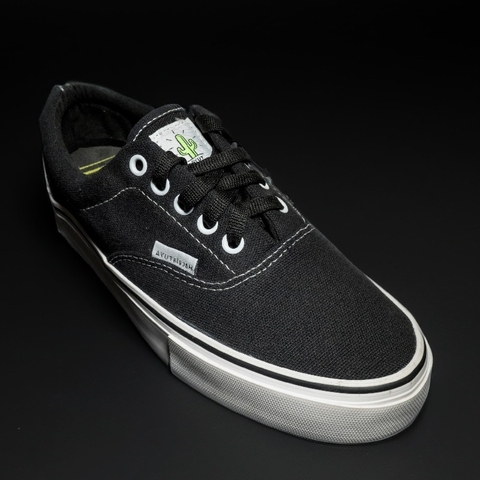 Un zapato negro de tela con detalles en blanco y una etiqueta en la parte superior.