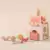 Castillo de actividades 5 en 1 en tonos rosa, con piezas de formas geométricas, diseñado para juegos musicales y de exploración.