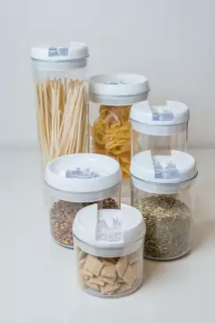 Conjunto de cinco frascos redondos de acrílico con tapa hermética, organizados en una mesa, conteniendo fideos, especias y otros alimentos.