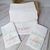 Kit de fraldas personalizadas em tecido branco com bordado em monograma rosa e verde, ideal para meninas.